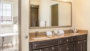 Un baño con bañera, un espejo grande, un lavabo con tocador y un perchero para toallas.
