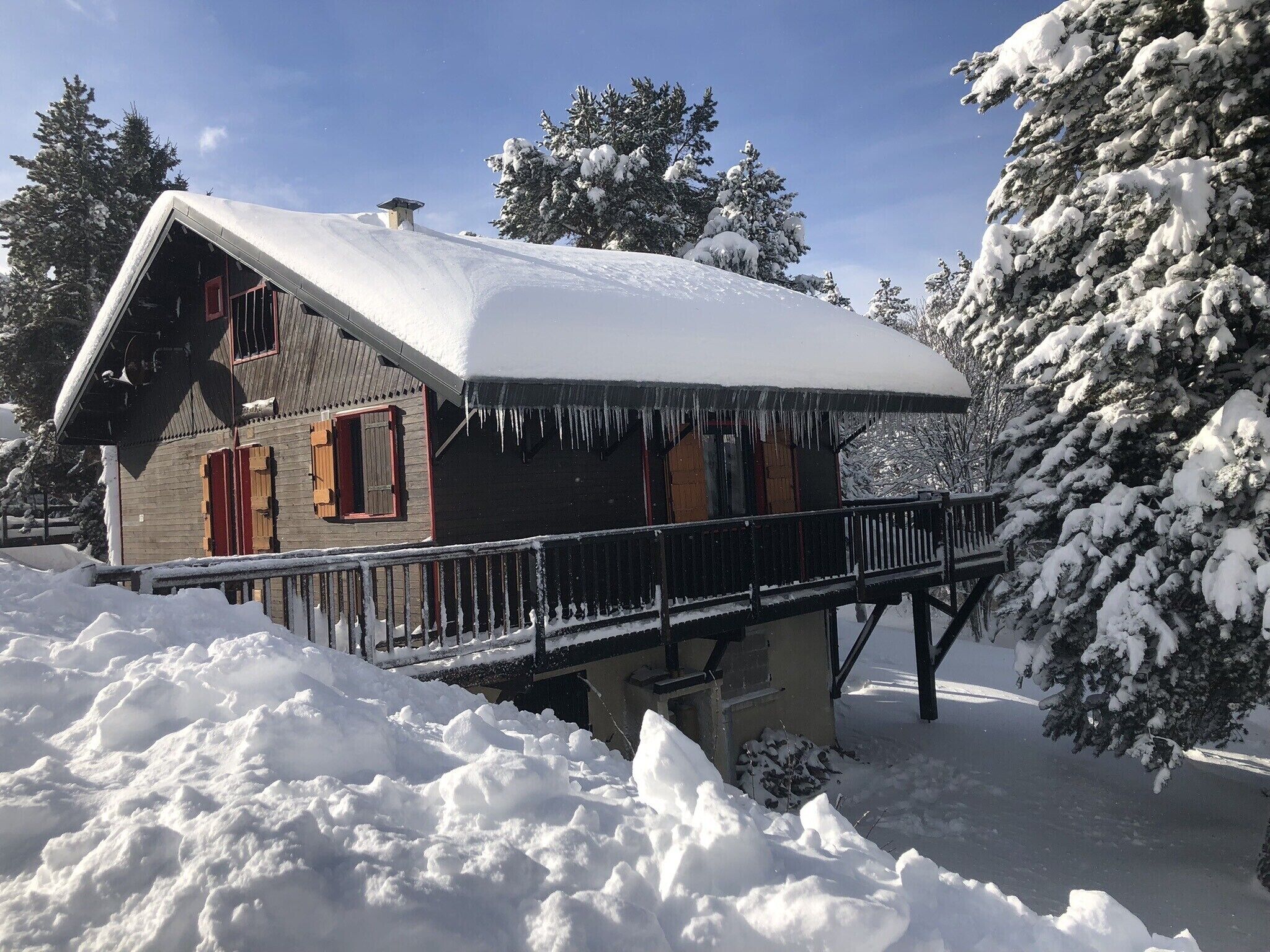 Een houten chalet met een met sneeuw bedekte dak en een balkon.