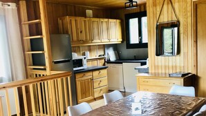 A wooden cabin interior with a dining table, chairs, a kitchen area, and a window. - Cosy chalet close to resorts and lake many activities summer/winter 10 pl. ⛷️🥾🦌 (Matemale)
