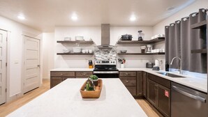 A modern kitchen with a central island, built-in oven, and stainless steel appliances.