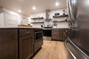 A modern kitchen with dark wood cabinets, stainless steel appliances, and a white backsplash.