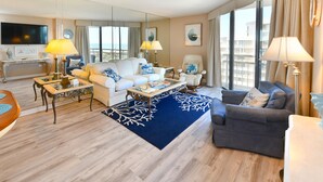A modern hotel room with a living area featuring a sofa set, a coffee table, and a TV.