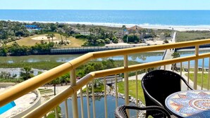 A balcony with a view of a beach, a lake, and a golf course.