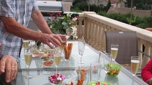 A glass table with various food items and drinks, surrounded by chairs.