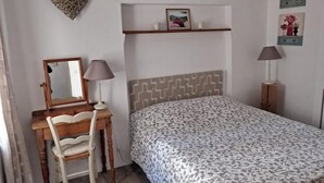 Une chambre à coucher avec un lit, un bureau et une chaise, un miroir et deux lampes de chevet.