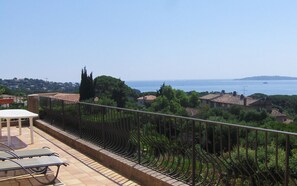 A terrace with a view of the sea, a table, and chairs. - "villa Mona" à 700 m de la mer (GRIMAUD)
