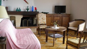 Una sala de estar con chimenea, televisión y una mesa de comedor con sillas.