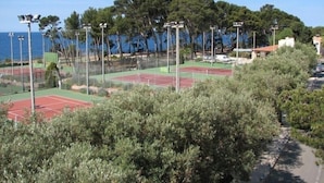 A tennis court complex with multiple courts, surrounded by trees and a view of the sea. - Renecros 1 à 30 m de la mer (BANDOL)