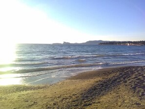 Enjoy the serene coastal scenery with gentle waves and distant hills.