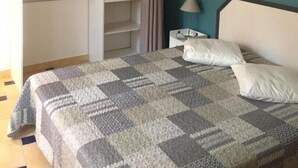 A bedroom with a bed, a nightstand, a wardrobe, and a wall with a botanical print. - La Cigale Bleue à Callian (CALLIAN)