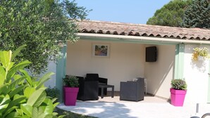 An outdoor patio area with seating, a tiled roof, and potted plants. - La Cigale Bleue à Callian (CALLIAN)