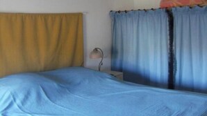 Ein Schlafzimmer mit Bett, Vorhängen, einem Bild an der Wand und einer Lampe.