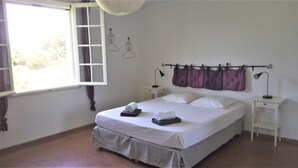 A bedroom with a bed, two bedside tables, a window with curtains, and a wall-mounted towel rack. - Le Bastidon des Tilleuls (LE BEAUSSET)