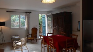 Un comedor con una mesa dispuesta para cuatro, un aparador de madera y un televisor sobre un mueble.