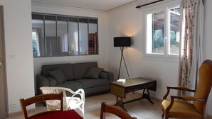 Una sala de estar con un sofá, una mesita, una lámpara de pie y dos sillones.
