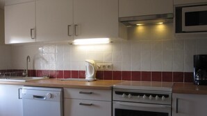 Een keuken met witte kastjes, een magnetron, een fornuis en een vaatwasser.