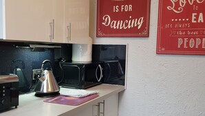 A modern kitchen with white cabinets, a kettle, a microwave, and a coffee maker. There are two motivational posters on the wall. - 6 Person - 1 - Bed Apartment in Blackpool (Blackpool)