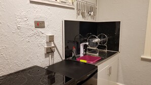 A compact kitchen with a black stove, white cabinets, and a backsplash. - 6 Person - 1 - Bed Apartment in Blackpool (Blackpool)