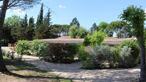 A building with a tiled roof, surrounded by various trees and shrubs. - La Cigale Verte à Callian (CALLIAN)