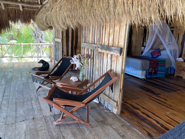 A wooden deck with two lounge chairs, a small table, and a bed with a canopy.