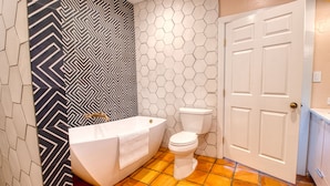 Un baño con una bañera blanca, un inodoro blanco y una puerta blanca.