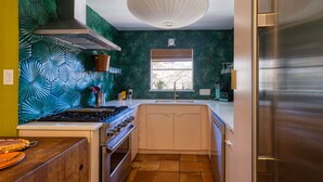 Cocina compacta con estufa a gas, horno y refrigerador de acero inoxidable.