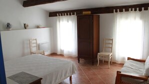 Een slaapkamer met een bed, twee stoelen, een kledingkast en een radiator.