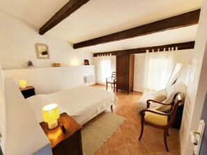 Een slaapkamer met een bed, nachtlampje, stoel en een kledingkast.
