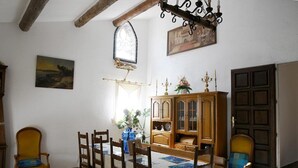 Ein Essbereich mit Holztisch und Stühlen, einem Schrank mit Glastüren, einem Fenster mit Zierrahmen und einer Kristallleuchter.