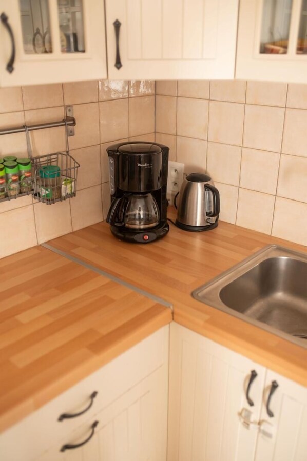 A kitchen with wooden countertops, a coffee maker, a kettle, and a spice rack.