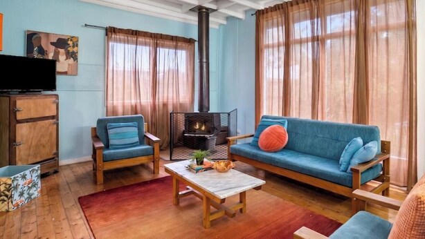 Un salon comprenant un canapé, deux fauteuils, une table basse, une cheminée, un téléviseur et une lampe.