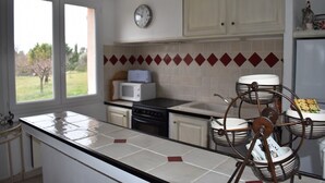Une cuisine avec une fenêtre, un four à micro-ondes, une cuisinière et un égouttoir à vaisselle.