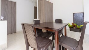 Een eethoek met een rechthoekige tafel, zes stoelen en een potplant op een vensterbank.