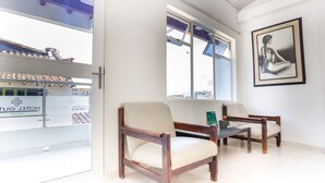 Une chambre d’hôtel avec deux chaises en bois, une petite table et une grande fenêtre donnant sur l’extérieur.
