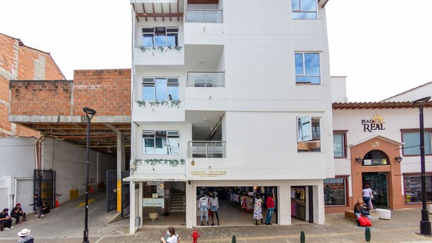 Un hôtel à plusieurs étages, avec une entrée au niveau du sol, des balcons et une devanture bien visible portant le nom « Plaza Real ».