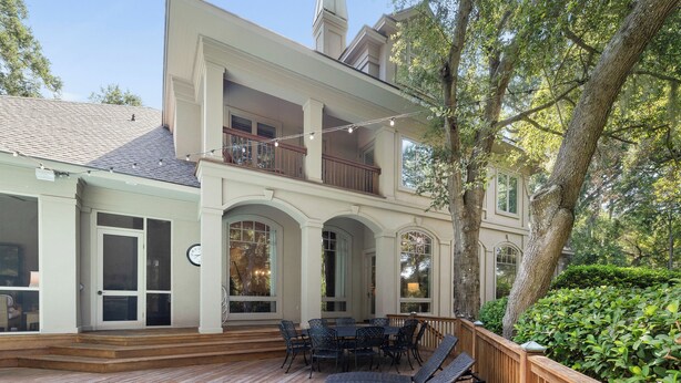 A two-story house with a covered patio, outdoor seating, and a swimming pool.
