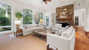 A spacious living room with a fireplace, large windows, and a stone accent wall.