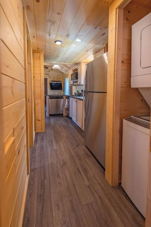 A wooden cabin interior with a kitchen area, including a refrigerator, microwave, and wooden cabinets.