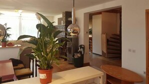 A living room with a dining area, a potted plant, a hanging light fixture, and a staircase leading to another level. - Beautiful 3-bedroom apartment with lake view (Radovljica)