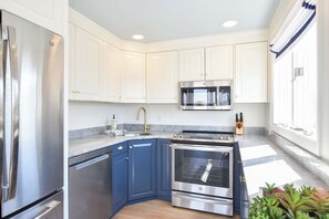 A modern kitchen with white cabinets, a stainless steel refrigerator, a double oven, and a microwave.