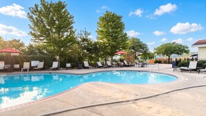 A swimming pool with lounge chairs and umbrellas, surrounded by trees. - Branson | Pool & Mountains | Scenic Ozark Stay (Banson)
