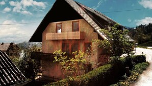 A traditional chalet with a sloped roof, wooden balcony, and a stone foundation. - Beautiful house with lake view, for large groups! (Radovljica)