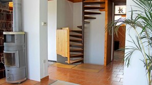 A modern interior with a wood-burning stove, a spiral staircase, and a potted plant. - Beautiful house with lake view, for large groups! (Radovljica)