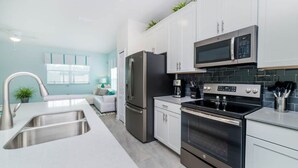 Una cocina moderna con electrodomésticos de acero inoxidable, armarios blancos y un salpicadero de azulejos negros.