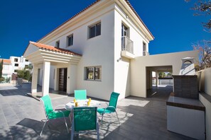 Stylish two-story residence with a balcony, patio, and outdoor seating area.