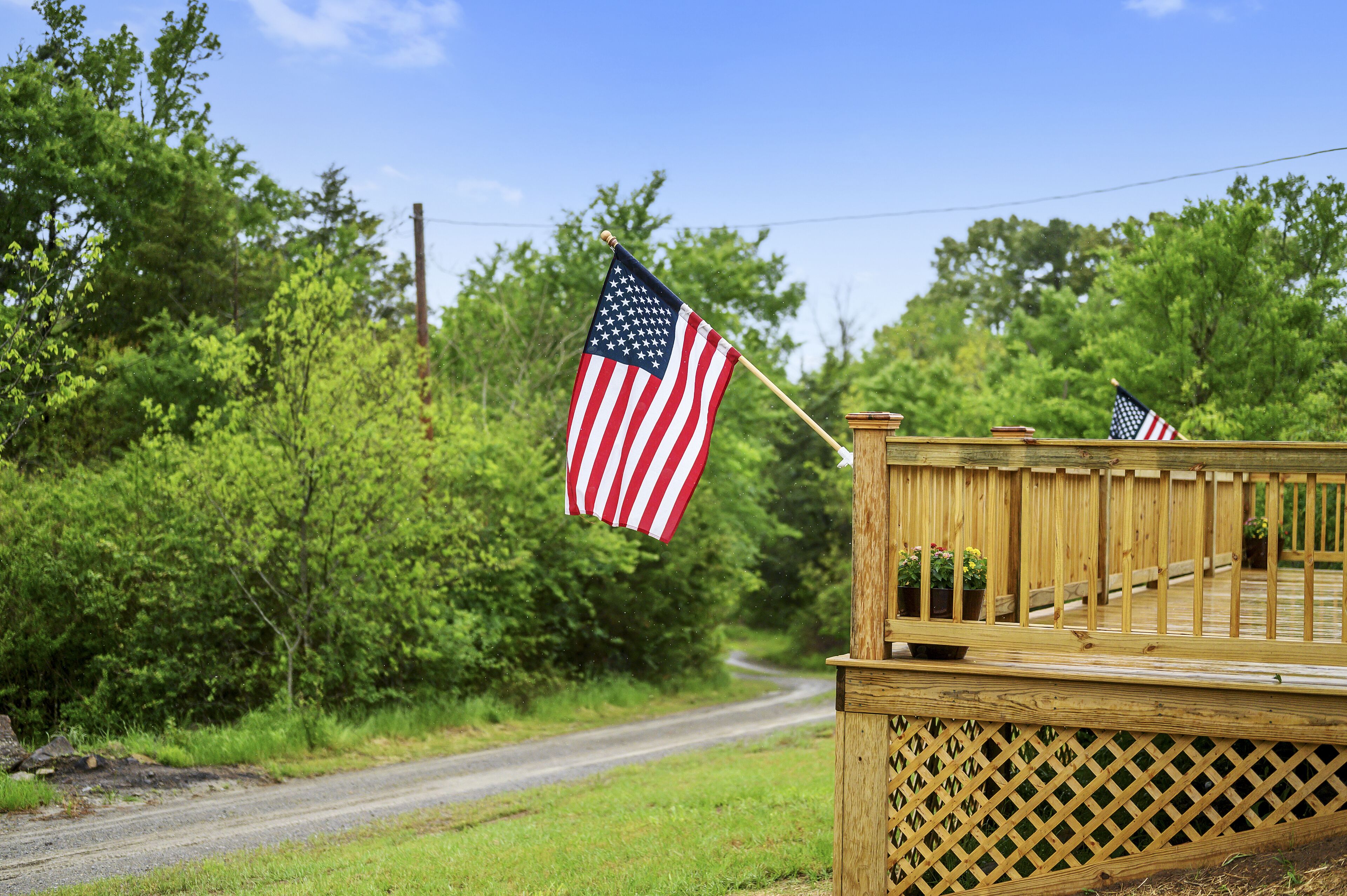 Een houten terras met een spijlenhek en twee Amerikaanse vlaggen.
