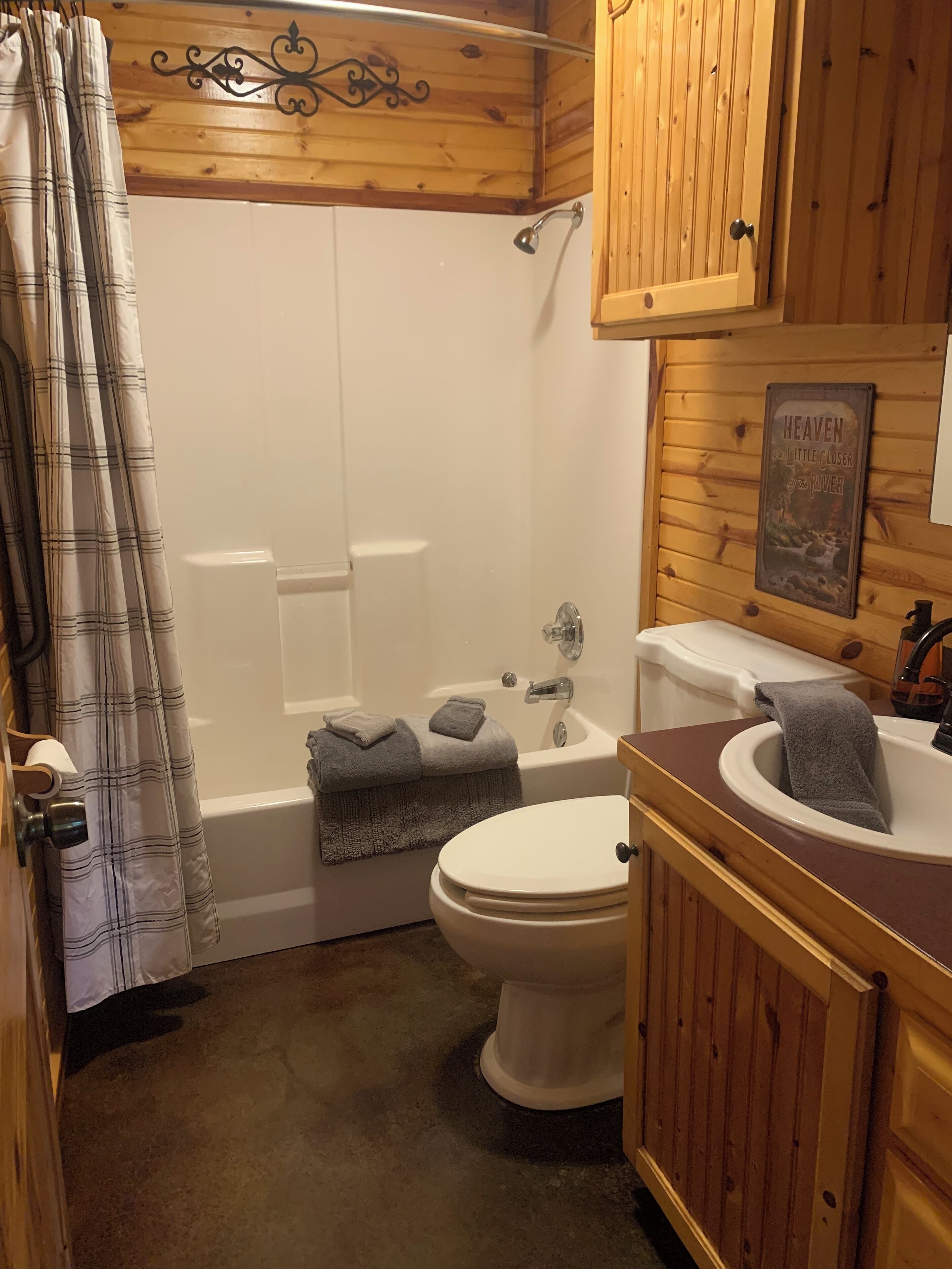 Un baño con techo de madera, bañera, inodoro y lavamanos.