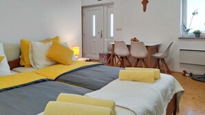 A hotel room with two beds, a dining area with chairs, a small table, and a window with plants. - Studio with Terrace – Nature Stay near Terme Čatež (Ribnica)