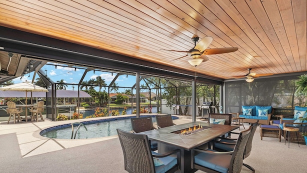 An outdoor patio with a pool, dining area, and lounge seating. - Sunny Cape Coral Pool Home (Cape Coral)
