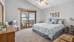 A bedroom with a bed, a ceiling fan, a desk, a chair, and a view through a sliding glass door. - The Lake Shack-----Water Front!!! (Brownwood)